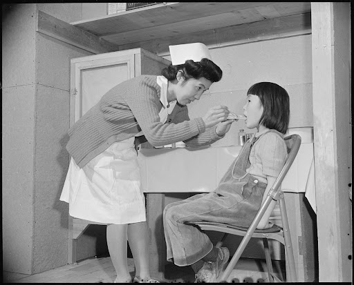 Nurse checking child's throat with tongue depressor